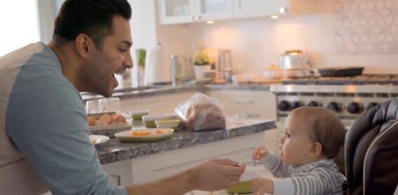 Johnson & Johnson brand advertising — a father feeding his baby in a kitchen